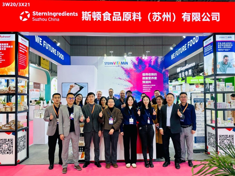 Gruppe von Mitarbeitenden am SternVitamin-Messestand auf einer internationalen Messe, lächelnd und Daumen hoch.