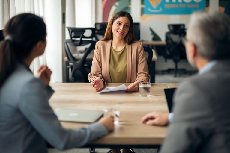 Bewerberin im Gespräch mit zwei Personalverantwortlichen in einem modernen Büro.