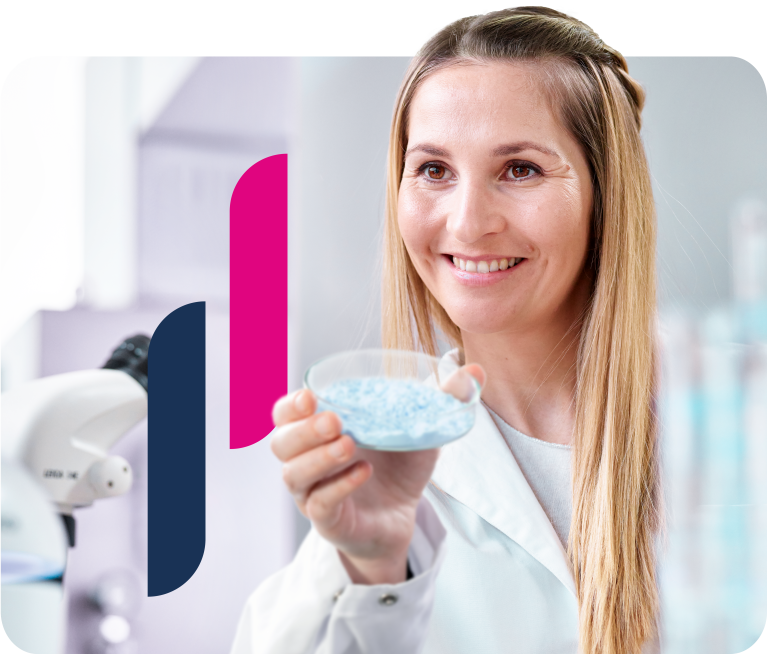 Frau hält im Labor eine Petrischale mit blauem Pulver hoch.  