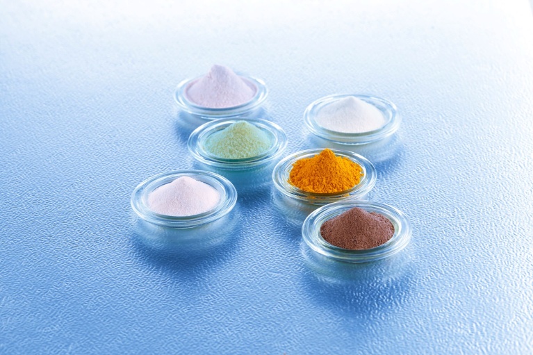 Unterschiedliche Vitaminpulver in kleines Glasschalen auf blauem Hintergrund angeordnet. 