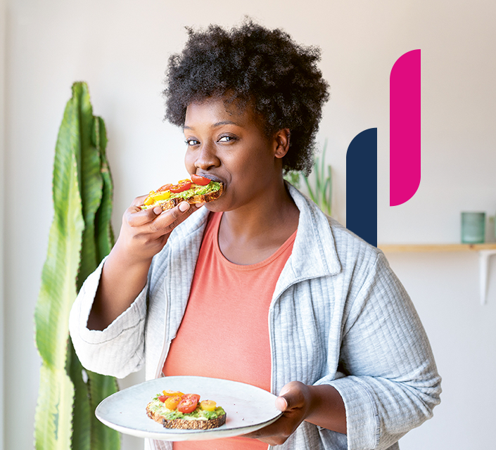 Frau isst ein gesundes Avocado-Brot mit Tomaten von einem Porzellanteller.